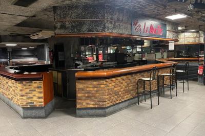 Salle vide avec un sol en carrelage gris foncé, des murs clairs et des portes rouges visibles en arrière-plan.