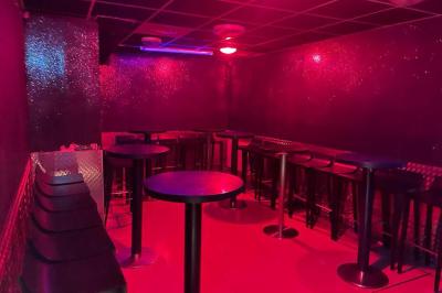 Salle vide avec un sol en carrelage gris foncé, des murs clairs et des portes rouges visibles en arrière-plan.