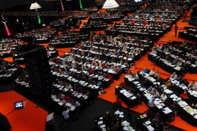 Bâtiment moderne avec façade vitrée, éclairé au crépuscule, reflété dans un plan d'eau calme.