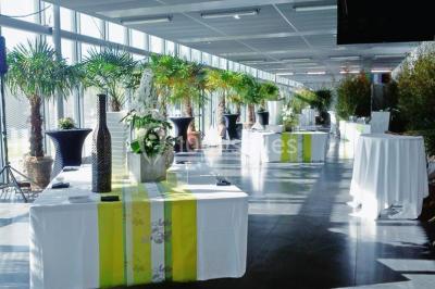 Bâtiment moderne avec façade vitrée, éclairé au crépuscule, reflété dans un plan d'eau calme.