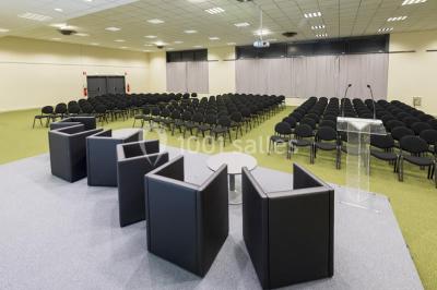 Bâtiment moderne avec façade vitrée, éclairé au crépuscule, reflété dans un plan d'eau calme.