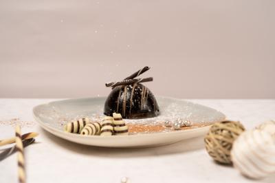 Assiette rectangulaire avec boule de glace au chocolat, boule de glace vanille, gaufre, éclats de noisettes et sucre glace.
