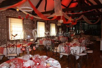Salle de réunion avec des tables blanches, des chaises en osier et un écran de projection, dans un cadre en briques…