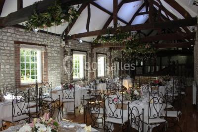 Salle de réunion avec des tables blanches, des chaises en osier et un écran de projection, dans un cadre en briques…