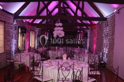 Salle de réunion avec des tables blanches, des chaises en osier et un écran de projection, dans un cadre en briques…