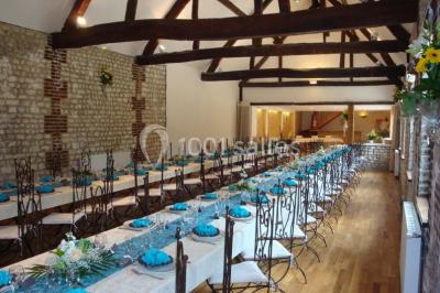 Salle de réunion avec des tables blanches, des chaises en osier et un écran de projection, dans un cadre en briques…