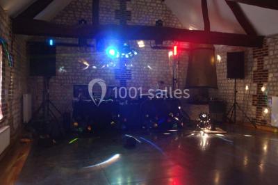 Salle de réunion avec des tables blanches, des chaises en osier et un écran de projection, dans un cadre en briques…