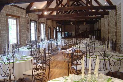 Salle de réunion avec des tables blanches, des chaises en osier et un écran de projection, dans un cadre en briques…