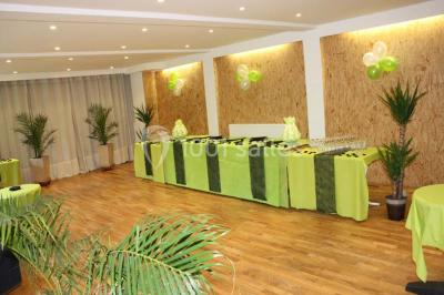 Salle de réunion avec des tables blanches, des chaises en osier et un écran de projection, dans un cadre en briques…