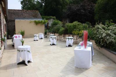 Salle de réunion avec des tables blanches, des chaises en osier et un écran de projection, dans un cadre en briques…