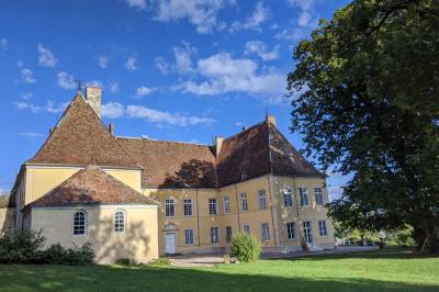 Façade d'un grand bâtiment ancien éclairé la nuit, entouré de petites lumières au sol.