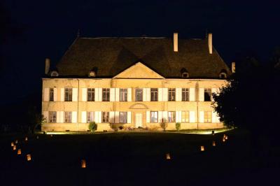 Façade d'un grand bâtiment ancien éclairé la nuit, entouré de petites lumières au sol.