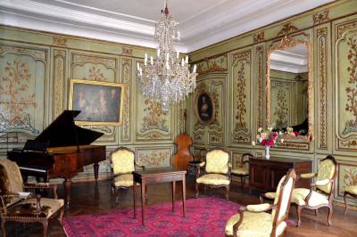 Façade d'un grand bâtiment ancien éclairé la nuit, entouré de petites lumières au sol.