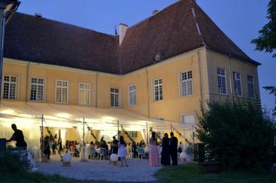 Façade d'un grand bâtiment ancien éclairé la nuit, entouré de petites lumières au sol.