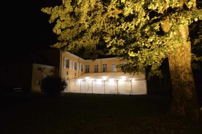 Façade d'un grand bâtiment ancien éclairé la nuit, entouré de petites lumières au sol.
