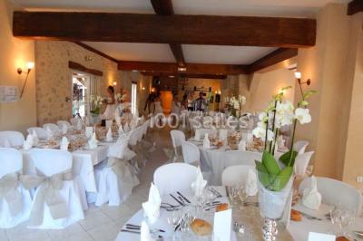 Façade d'une maison en pierre avec toit en ardoise, fenêtres symétriques et jardin clôturé au premier plan.