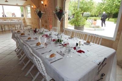 Façade d'une maison en pierre avec toit en ardoise, fenêtres symétriques et jardin clôturé au premier plan.