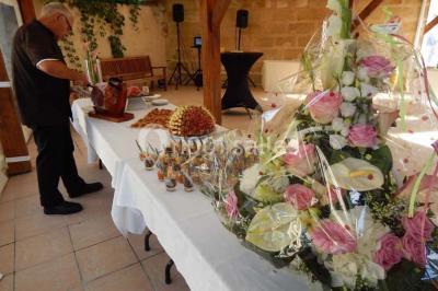 Façade d'une maison en pierre avec toit en ardoise, fenêtres symétriques et jardin clôturé au premier plan.
