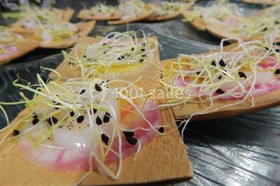 Façade d'une maison en pierre avec toit en ardoise, fenêtres symétriques et jardin clôturé au premier plan.