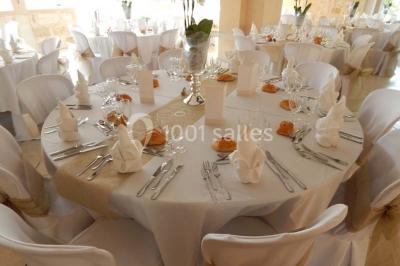 Façade d'une maison en pierre avec toit en ardoise, fenêtres symétriques et jardin clôturé au premier plan.