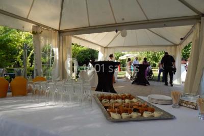 Façade d'une maison en pierre avec toit en ardoise, fenêtres symétriques et jardin clôturé au premier plan.