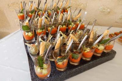 Façade d'une maison en pierre avec toit en ardoise, fenêtres symétriques et jardin clôturé au premier plan.