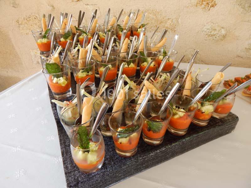 Verrines variées disposées sur un plateau, contenant des préparations colorées et décorées avec des cuillères et des…