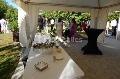 Façade d'une maison en pierre avec toit en ardoise, fenêtres symétriques et jardin clôturé au premier plan.