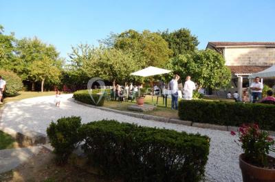 Façade d'une maison en pierre avec toit en ardoise, fenêtres symétriques et jardin clôturé au premier plan.