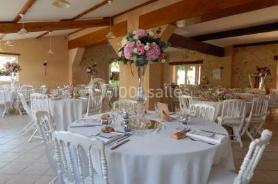 Façade d'une maison en pierre avec toit en ardoise, fenêtres symétriques et jardin clôturé au premier plan.