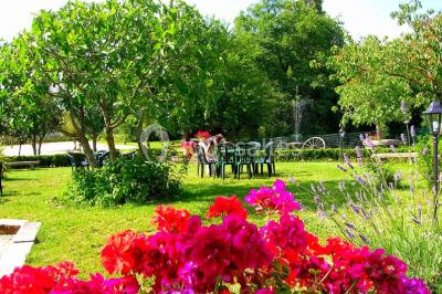 Façade d'une maison en pierre avec toit en ardoise, fenêtres symétriques et jardin clôturé au premier plan.