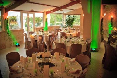 Façade d'une maison en pierre avec toit en ardoise, fenêtres symétriques et jardin clôturé au premier plan.