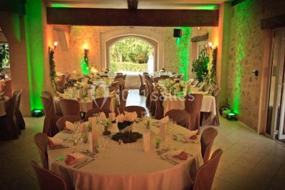 Façade d'une maison en pierre avec toit en ardoise, fenêtres symétriques et jardin clôturé au premier plan.