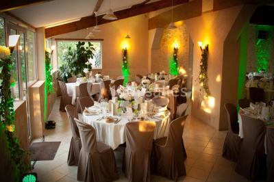 Façade d'une maison en pierre avec toit en ardoise, fenêtres symétriques et jardin clôturé au premier plan.