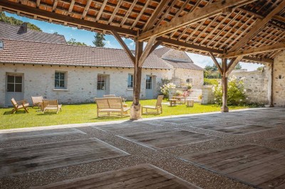 Miniature Location salle Aincourt (Val-d'Oise) - Domaine de Brunel - La Remise #3 Paysage champêtre avec un arbre pleureur, des fleurs bleues au premier plan et un champ sous un ciel partiellement nuageux.