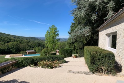 Tentes blanches pointues installées dans un jardin paysager avec vue sur une vallée boisée sous un ciel partiellement…