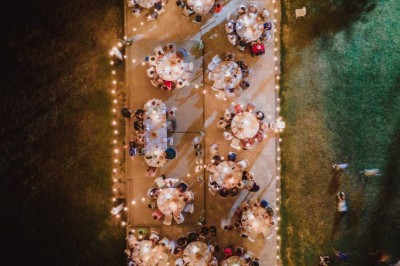 Tentes blanches pointues installées dans un jardin paysager avec vue sur une vallée boisée sous un ciel partiellement…