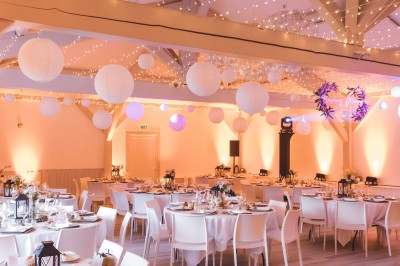 Tentes blanches pointues installées dans un jardin paysager avec vue sur une vallée boisée sous un ciel partiellement…