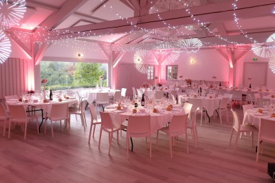 Tentes blanches pointues installées dans un jardin paysager avec vue sur une vallée boisée sous un ciel partiellement…