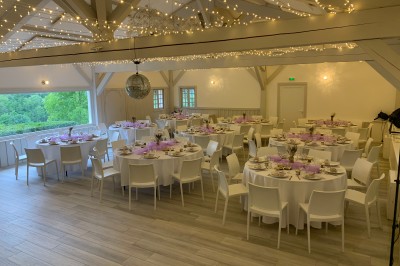 Tentes blanches pointues installées dans un jardin paysager avec vue sur une vallée boisée sous un ciel partiellement…