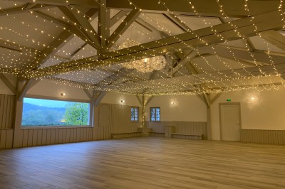 Tentes blanches pointues installées dans un jardin paysager avec vue sur une vallée boisée sous un ciel partiellement…