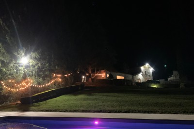 Tentes blanches pointues installées dans un jardin paysager avec vue sur une vallée boisée sous un ciel partiellement…