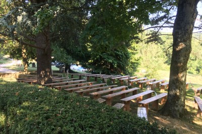 Tentes blanches pointues installées dans un jardin paysager avec vue sur une vallée boisée sous un ciel partiellement…