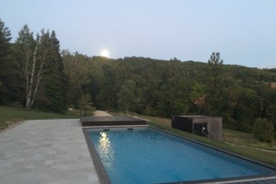 Tentes blanches pointues installées dans un jardin paysager avec vue sur une vallée boisée sous un ciel partiellement…