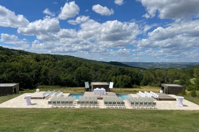 Salle de réception décorée avec des guirlandes lumineuses, des lampions suspendus et des tables dressées pour un événement.