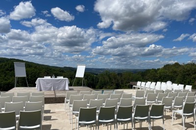 Salle de réception décorée avec des guirlandes lumineuses, des lampions suspendus et des tables dressées pour un événement.