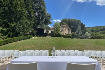 Salle de réception décorée avec des guirlandes lumineuses, des lampions suspendus et des tables dressées pour un événement.