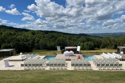 Salle de réception décorée avec des guirlandes lumineuses, des lampions suspendus et des tables dressées pour un événement.