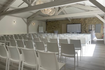 Salle de réception décorée avec des guirlandes lumineuses, des lampions suspendus et des tables dressées pour un événement.