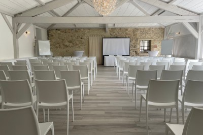 Salle de réception décorée avec des guirlandes lumineuses, des lampions suspendus et des tables dressées pour un événement.